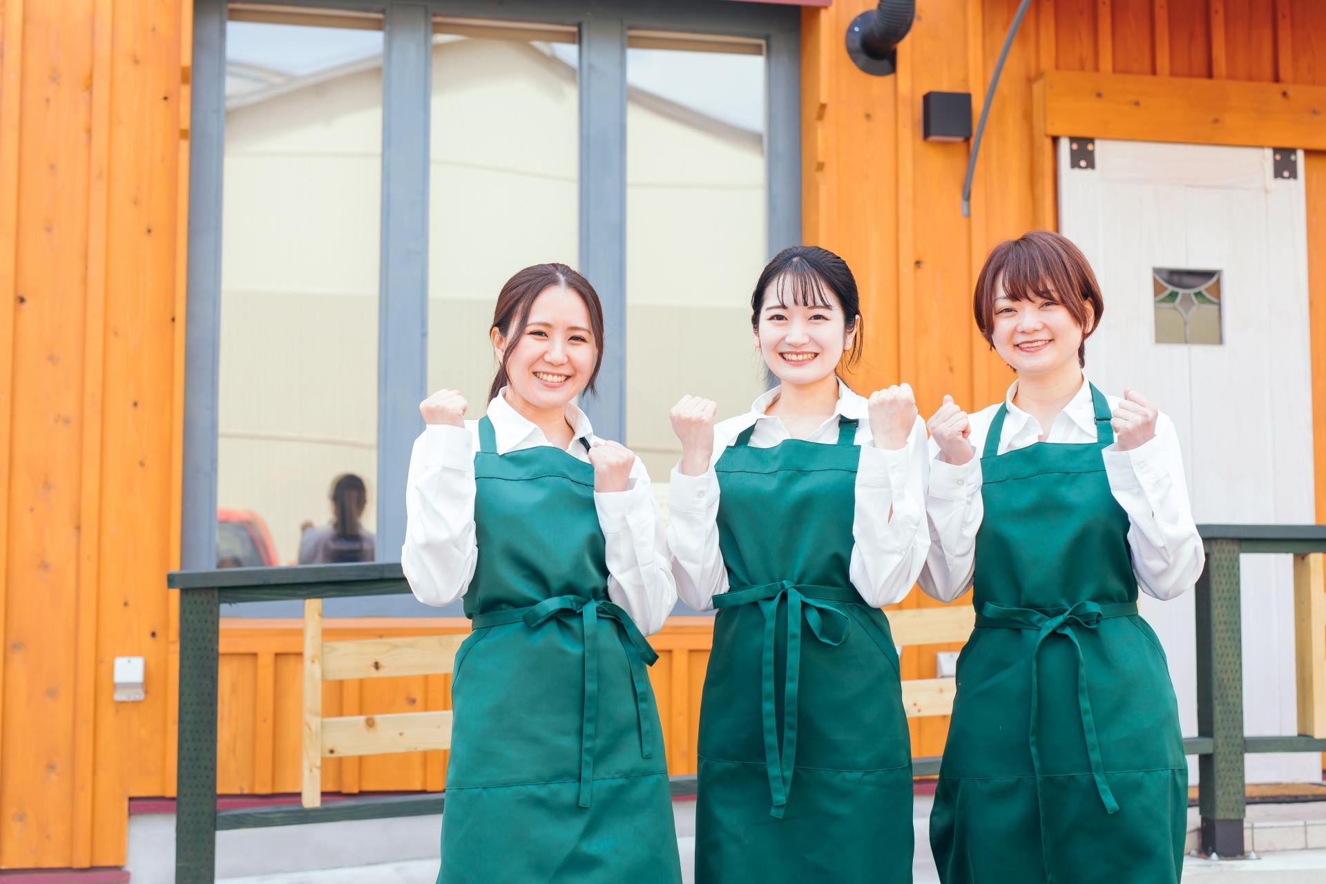 ガッツポーズをしている三人の女性カフェ店員