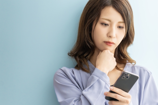 スマホの画面を見ながら悩んでいる女性